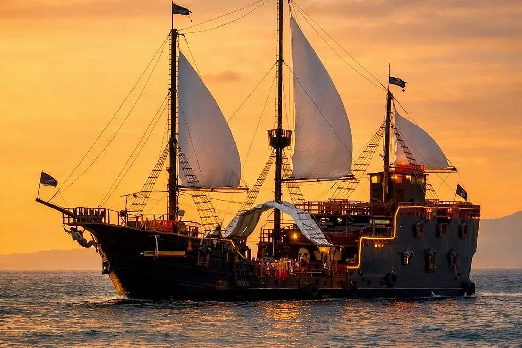 The Puerto Vallarta pirate ship under white sails at sunset on Banderas Bay